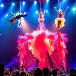 Circus Oz acrobats performing in colorful costumes at night.