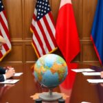 Trump and Putin meeting with flags in the background.